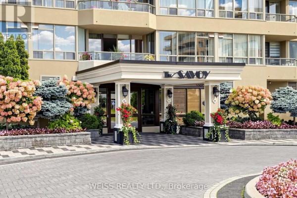 View of the building entrance sign that reads "LA SAVOY" with landscaping and trees. - 2104 - 10 Torresdale Avenue, Toronto