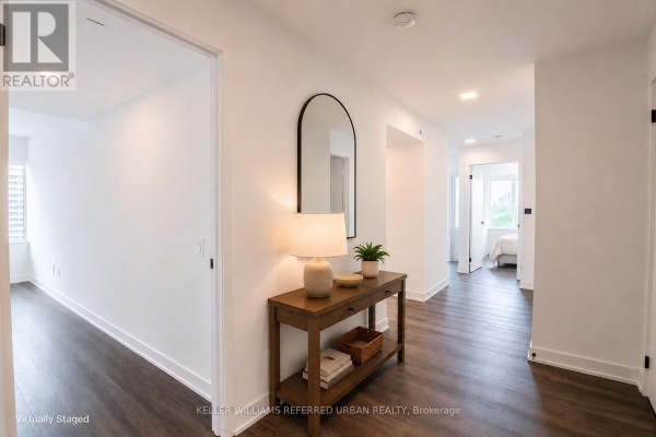 Hallway with white walls, a dark wood floor, and a console table with a mirror. - 2104 - 609 Sherbourne Street, Toronto
