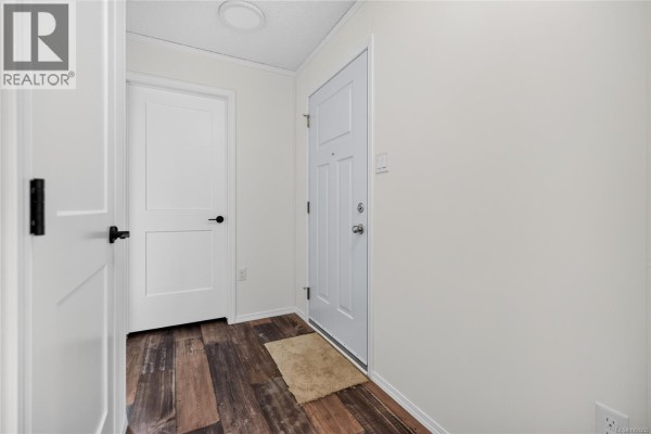 Interior hallway with white doors, white walls, and dark wood-look laminate flooring. - 2104 Pemberton Pl, Comox