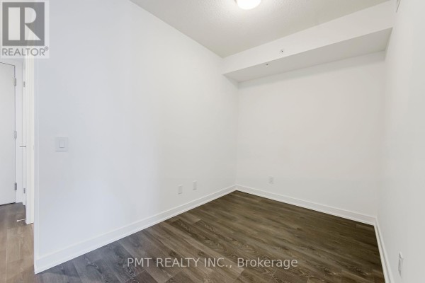 Empty bedroom with white walls, dark wood floors, and two white doors in the corner. - 2105 - 30 Samuel Wood Way, Toronto