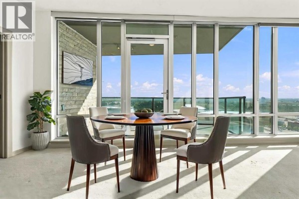 Round dining table with four chairs and place settings in front of floor-to-ceiling windows. - 2106, 210 15 Avenue Se, Calgary
