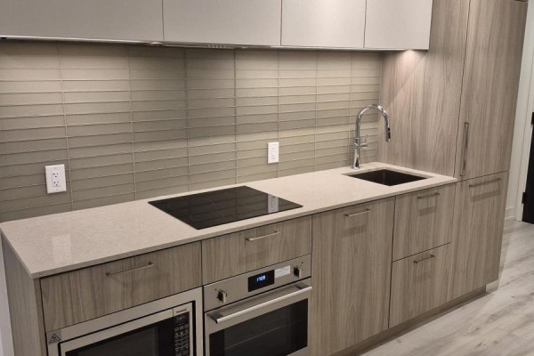Compact kitchen with light wood cabinets, quartz countertop, and induction cooktop. - 2106 - 36 Olive Avenue, Toronto