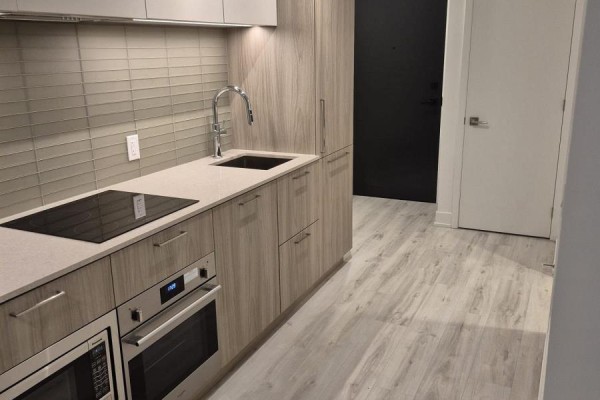 Kitchenette with light wood cabinets, stainless steel appliances, and grey wood-look flooring. - 2106 - 36 Olive Avenue, Toronto