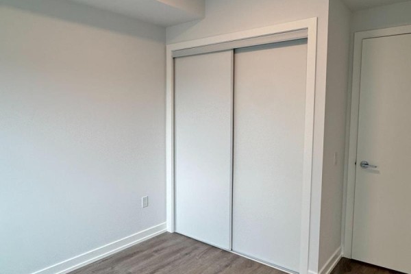Interior wall with a white sliding closet door and a standard white interior door. - 2106 - 5 Meadowdale Road, Vaughan
