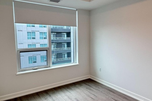 Bedroom with a large window showing a view of the neighboring building and a light wood floor. - 2106 - 5 Meadowdale Road, Vaughan