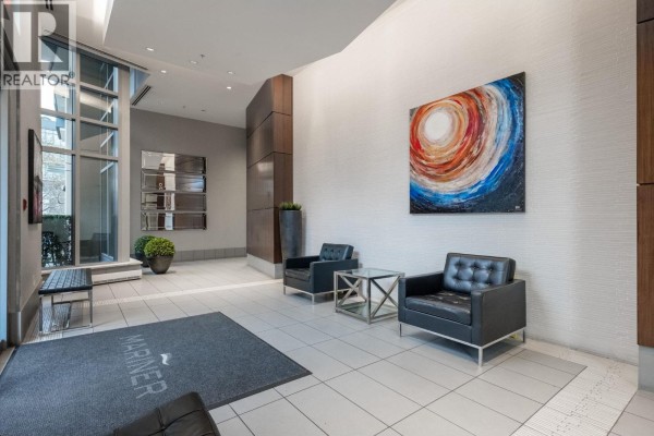 Building lobby with tiled floor, two black leather chairs, and abstract art. - 2106 918 Cooperage Way, Vancouver
