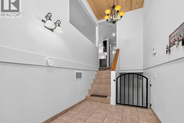 Backyard with a brick pathway running alongside large evergreen trees and a green lawn. - 21066 Glenwood Avenue, Maple Ridge