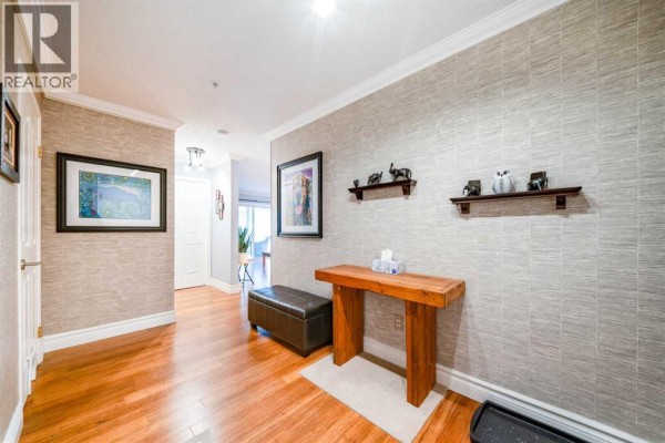 Apartment entryway with hardwood floors, textured wallpaper, and a wooden console table. - 2107, 20 Harvest Rose Park Ne, Calgary