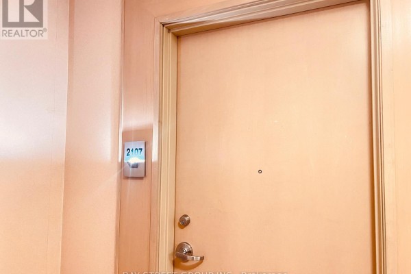 Apartment door number 2107 illuminated on a peach-colored wall. - 2107 - 60 Byng Avenue, Toronto
