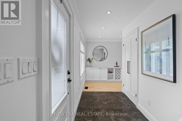 Hallway with white doors, dark floor tiles, and view into room with cabinets. - 2107 Russett Road, Mississauga