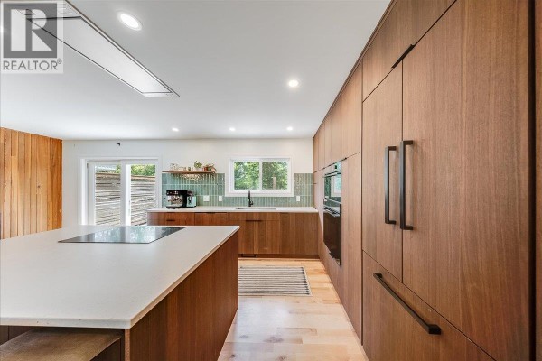 Modern kitchen with wood cabinets, white quartz island, and mint green tile backsplash. - 2108 Third Avenue, Rossland