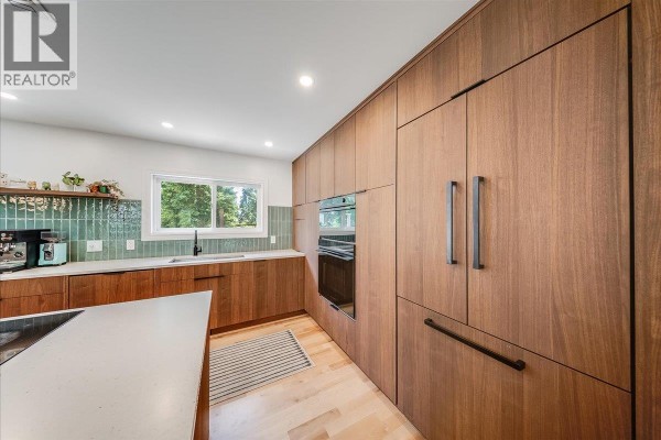 Contemporary kitchen with dark wood cabinetry, stainless steel appliances, and a white quartz island. - 2108 Third Avenue, Rossland