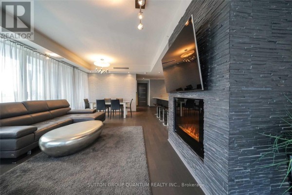 Living and dining area with sectional, fireplace, dining table, and view of the kitchen island. - 2109 - 180 University Avenue, Toronto