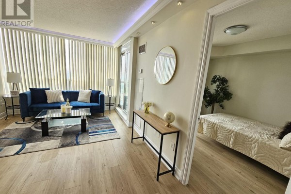 Living room with a blue sofa, glass coffee table, and beige walls with floor-to-ceiling windows. - 2109 - 60 Brian Harrison Way, Toronto