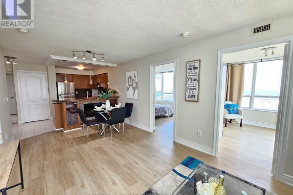 Open concept living and dining area with a breakfast bar, wooden floors, and city views. - 2109 - 60 Brian Harrison Way, Toronto