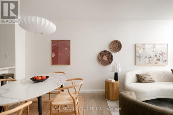 Dining area with a marble table and chairs, adjacent to a living area with a curved sofa. - 2109 - 750 Bay Street, Toronto