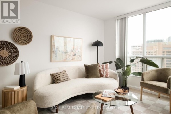 Living room with a bouclé sofa, glass coffee table, armchair, and large window with city views. - 2109 - 750 Bay Street, Toronto
