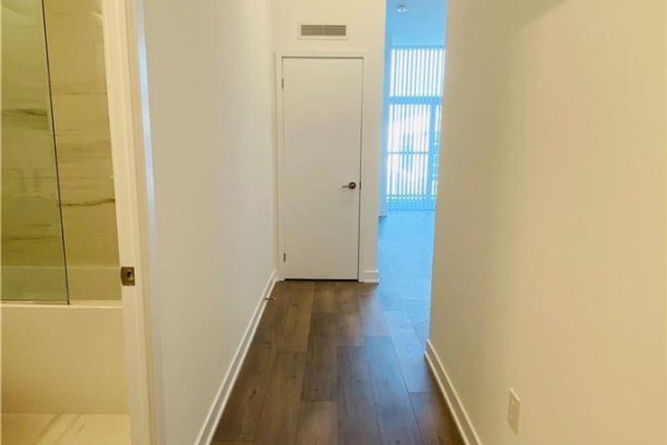 Interior hallway with wood-look flooring, white walls, and a white door. - 211 - 10 Honeycrisp Crescent, Vaughan