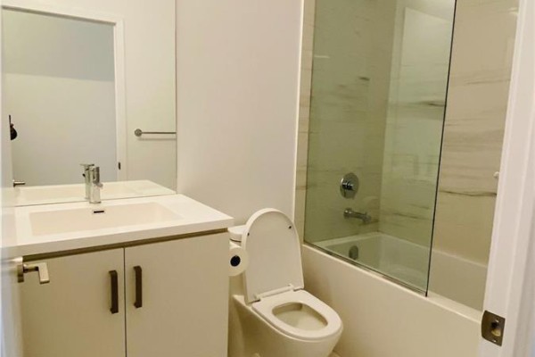 Bathroom with a white vanity, toilet, and bathtub with a glass enclosure. - 211 - 10 Honeycrisp Crescent, Vaughan