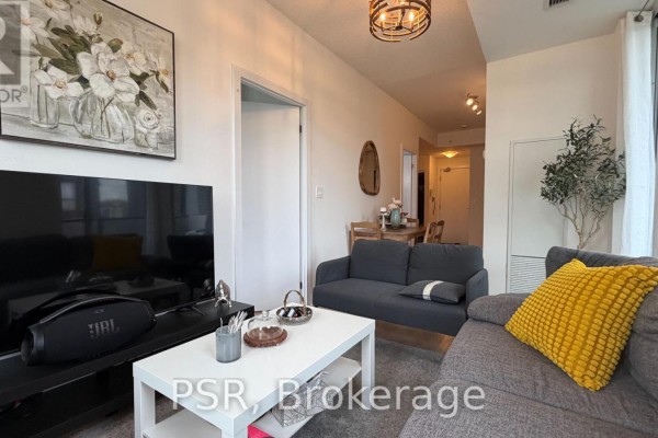 Living room with a grey sofa, white coffee table, and a doorway leading to a dining area. - 211 - 150 Fairview Mall Drive, Toronto