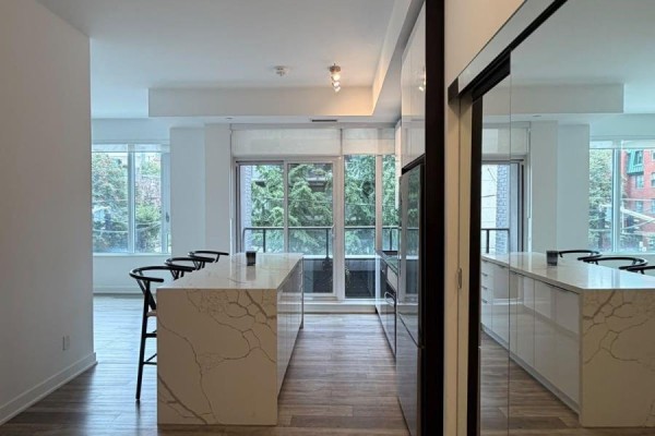 Modern kitchen with large island, pendant lights, and large windows with trees. - 211 - 543 Richmond Street W, Toronto