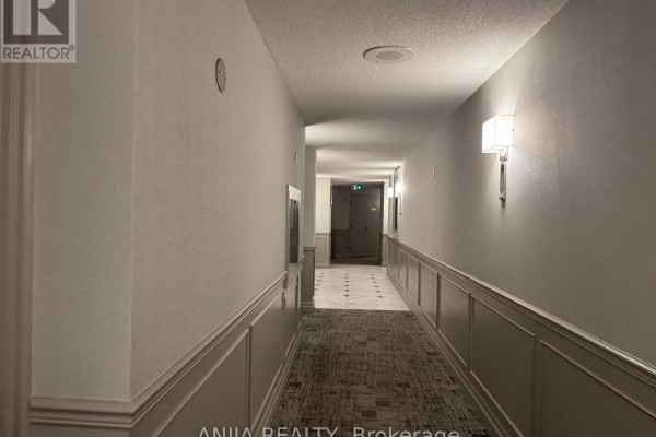 Interior apartment hallway with carpeted floor, wall sconces, and wainscoting details. - 211 - 75 York Mills Road, Toronto