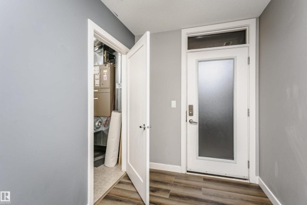 Modern kitchen with white cabinets, stainless steel appliances, and a grey tiled backsplash adjacent to a dining area. - #211 10808 71 Av Nw, Edmonton