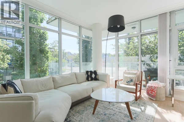 White kitchen with light wood floors, marble countertops, and large window. - 211 185 Victory Ship Way, North Vancouver
