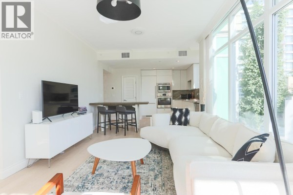 White kitchen featuring a corner sink, light wood floor, and street view. - 211 185 Victory Ship Way, North Vancouver