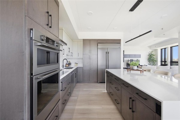Modern kitchen with grey cabinetry, stainless steel appliances, and a large white island. - 211 1924 St. Mary's Road, Winnipeg