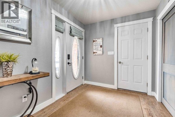 Interior entryway with gray walls, a tan rug, a console table, and double doors leading outside. - 211 4 Avenue Se, Three Hills