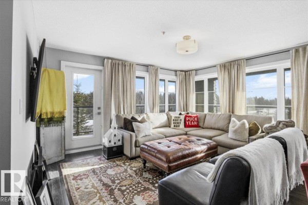 Apartment hallway with dark wood floors, white doors, and decorative items. - #211 5029 Edgemont Bv Nw, Edmonton
