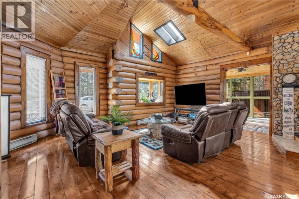 Living room featuring log walls, vaulted wood ceiling, stone fireplace, and leather recliners. - 211 Al Drive, Turtle Lake