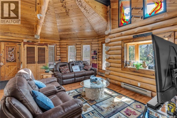 Living room with log walls, vaulted wood ceiling, stained glass windows, and leather sofas. - 211 Al Drive, Turtle Lake