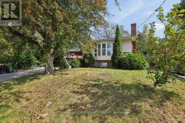 View of the house from the side lawn, showing windows and trees. - 211 Harcourt Avenue, Ottawa