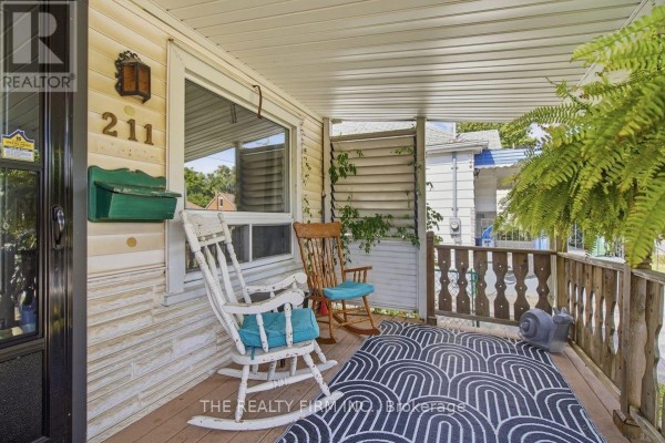 View of a porch with two rocking chairs, a rug, and a green mailbox on the exterior wall. - 211 Highbury Avenue N, London East