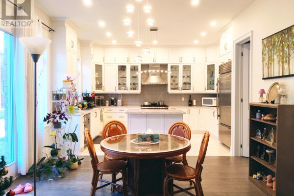 Modern kitchen with white cabinetry, island, dining table, and stainless steel appliances. - 211 Hillsview Drive, Richmond Hill