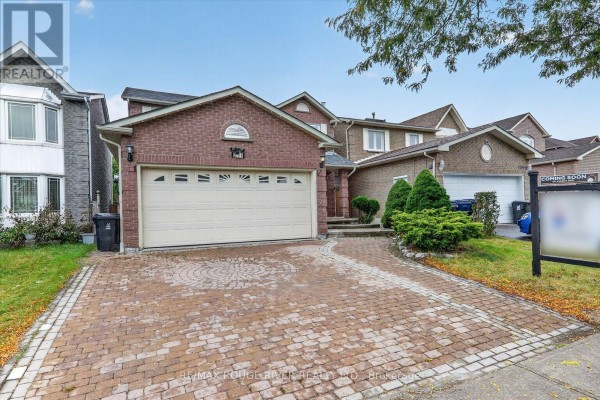 View of the brick house from the street, showing the garage and paved driveway. - 211 Ponymeadow Terrace, Toronto