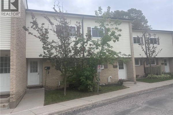 Close-up exterior view of a townhouse unit entrance with beige brick and white siding. - 211 Veronica Drive Unit# B24, Kitchener