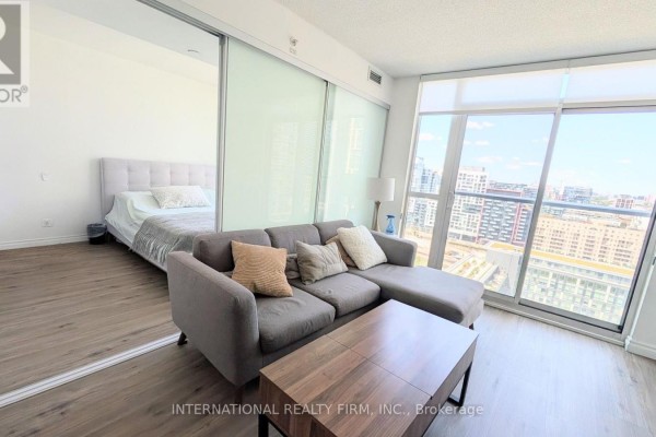 A modern kitchen with stainless steel appliances, dark wood cabinets, and white lower cabinets. - 2110 - 85 Queens Wharf Road, Toronto