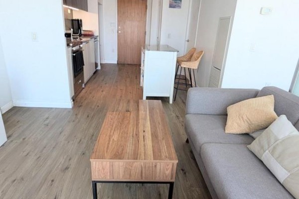 A kitchen with a granite island and two woven chairs, opening to a living area. - 2110 - 85 Queens Wharf Road, Toronto