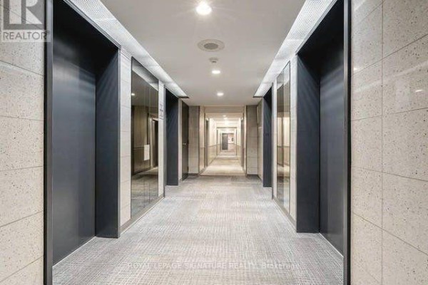 Hallway with tiled walls, recessed lighting, carpeted floor, and doors on both sides of the corridor. - 2112 - 285 Enfield Place, Mississauga