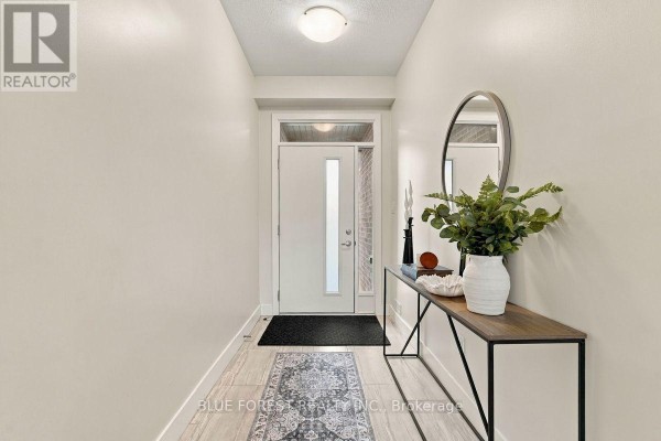 Entranceway with tiled floor, white door with frosted glass panel, and console table. - 2112 Meadowgate Boulevard, London South