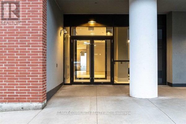 Building entrance with double glass doors, brick exterior, and large white column. - 2114 - 2550 Simcoe Street N, Oshawa
