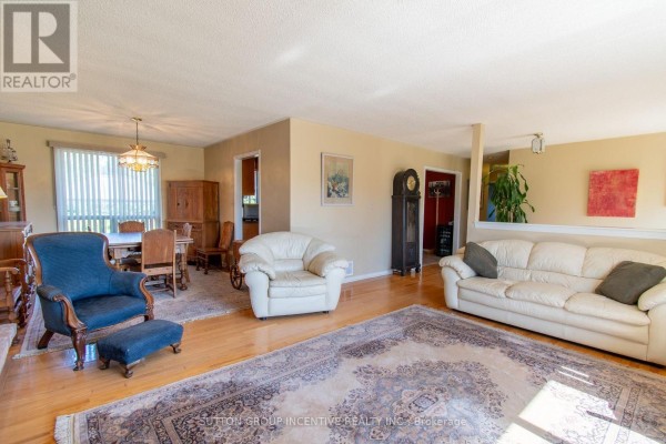 Living and dining room area with hardwood floors, light yellow walls, and large rugs. - 2114 Chantler Street, Innisfil