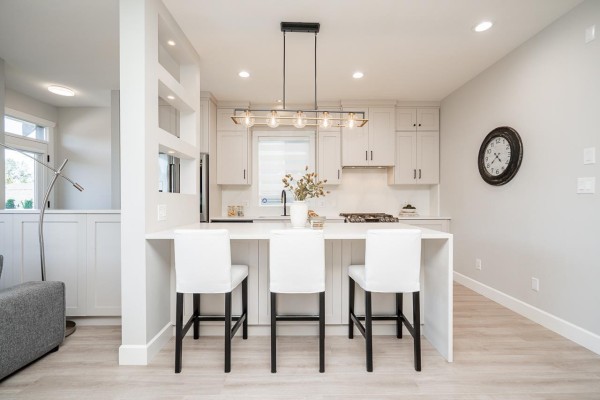 Kitchen island with white bar stools and pendant lights, facing the living room. - 21149 79a Avenue, Langley