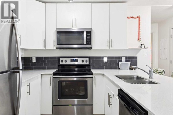 U-shaped kitchen featuring white cabinetry, dark subway tile backsplash, stainless steel appliances including a built-in microwave and oven. - 2115, 181 Skyview Ranch Manor Ne, Calgary