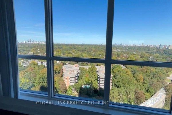 View through large window panes of the Toronto skyline and surrounding parkland. - 2115 - 585 Bloor Street E, Toronto
