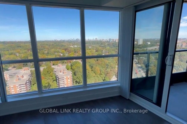 Corner view of apartment interior with expansive windows overlooking a tree-lined cityscape. - 2115 - 585 Bloor Street E, Toronto