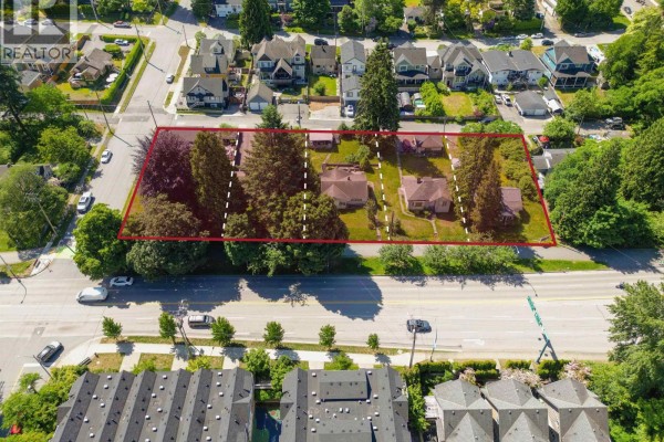 Front exterior of a small, older bungalow with a light-colored stucco finish and a gently sloping lawn. - 2115-2131 St Johns Street, Port Moody
